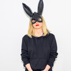 Serious blond woman wearing a rabbit mask with bunny ears