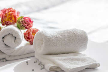 Close-up, white terry bath towels and flowers.