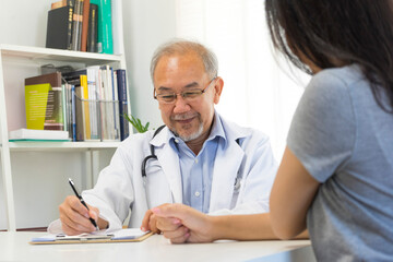 Old doctor in professional uniform examining young patient woman at hospital or medical clinic. Health care , medical and doctor staff service concept.