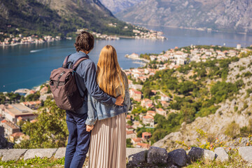 Couple woman and man tourists enjoys the view of Kotor. Montenegro. Bay of Kotor, Gulf of Kotor, Boka Kotorska and walled old city. Travel to Montenegro concept. Fortifications of Kotor is on UNESCO