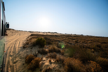 Desert landscape during a sunny day, seen from an all-terrain truck driving on the sand, during a...