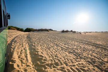 Desert landscape during a sunny day, seen from an all-terrain truck driving on the sand, during a...