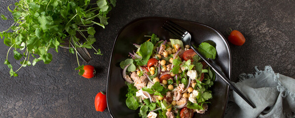 plate with salad with tuna, chickpeas and feta on a dark table