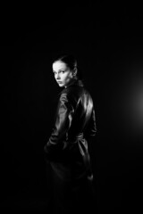 woman with closed eyes in leather coat and, black background