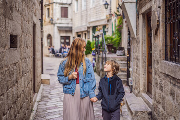 Obraz na płótnie Canvas Mom and son travelers enjoying Colorful street in Old town of Kotor on a sunny day, Montenegro. Travel to Montenegro concept