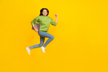 Full length photo of young girl active jumper rush hold laptop isolated over yellow color background