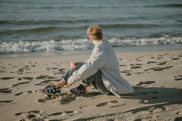 the guy sits on the sand looks towards the sea