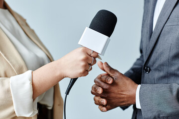 Side view closeup of young woman holding microphone while interviewing business expert - obrazy, fototapety, plakaty