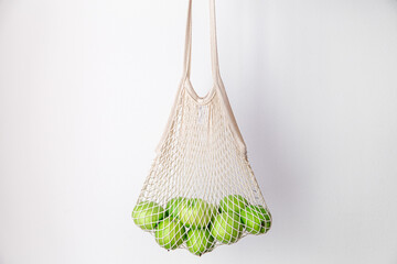 White string bag with green apples on a white background.