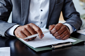 Close up of successful African American executive holding pen in hand while taking notes at business meeting