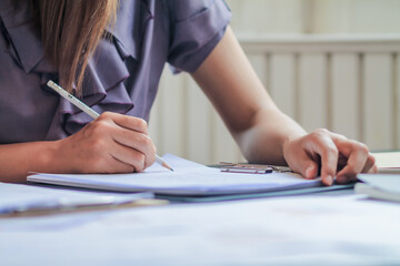 An accountant is examining a large amount of income and expense documents laying on their desks in their offices to summarize their annual results. Accounting concepts to summarize earnings