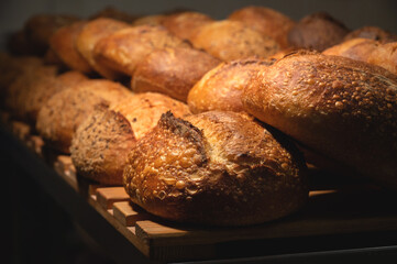 Fresh crispy hot delicious craft artisan bread. Many loaves lie on a wooden pallet