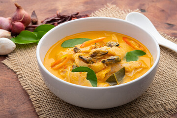 Red Curry with bamboo shoot and green mussel in Coconut Milk soup in white bowl on wood table.Asian food