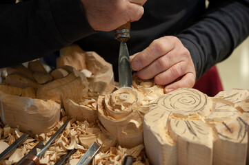 Master woodcarver at work. Wood shavings, gouges and chisels on the workbench.