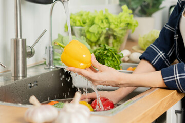 Close up hand of asian young housekeeper woman, washing sweet pepper, yellow paprika, vegetables...