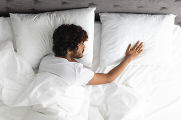 Top view of lonely guy touching pillow next to him