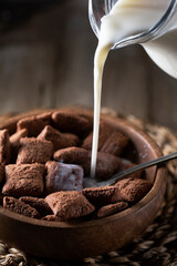 Chocolate pads of dry breakfast and milk on a wooden table