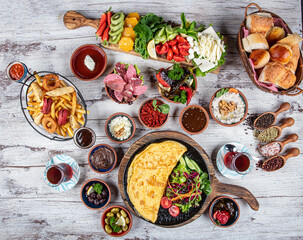 Turkish breakfast table. Pastries, vegetables, greens, olives, cheeses, omelette, spices, jams, honey, tea in a thermos, large composition. Breakfast concept in restaurant and cafe.