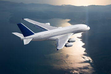 White double decker passenger plane in flight. Aircraft fly high above the sea during the sunset. View from above.