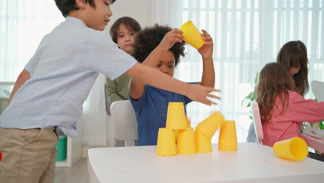 African American play stacking cup in the kindergarten classroom and naughty boy try falling cup stacking. Africa boy feeling angry and upset. Education and learning concept. Lifestyle in school