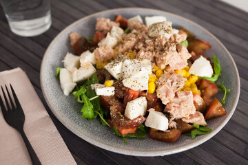 Fish salad with canned tuna and corn, tomatoes and arugula