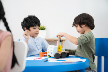 Two handsome boys sitting in the kindergarten school classroom and playing plant toys truck. Boy looking at the different shape of toys Learning, enjoy, education, playing concept