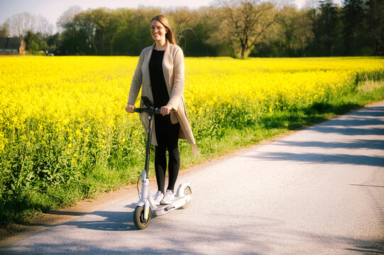 A woman rides an e-scooter through a sea of ​​yellow flowers
