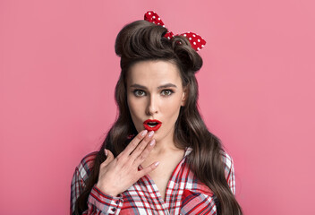 Surprised young pinup woman in retro clothes over cannot believe amazing offer or sale, covering mouth with hand