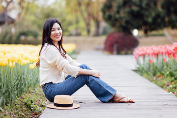 Candid lifestyle Portrait of happy young beautiful asian sexy woman enjoying life outdoor in park at spring. Smiling millennial girl with perfect clear glow skin and long brunette hair
