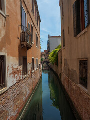 Fototapeta na wymiar Narrow, romantic canal on a sunny day in Venice.