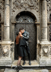 Fototapeta na wymiar Modern couple kissing near a black door. Lviv, Ukraine November 2, 2019