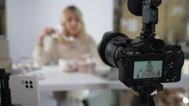 Young attractive Asian female blogger or vlogger looking at camera reviewing product. Modern businesswoman using social media for marketing. Business online influencer on social media concept.