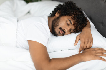 Closeup portrait of peaceful indian guy sleeping in bed