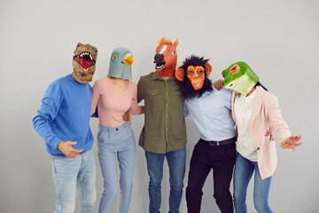 Portrait of cool eccentric diverse people in animal masks isolated on grey background hug show...