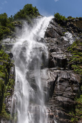 Obraz premium A mountain stream cascades down high cliffs in green nature.