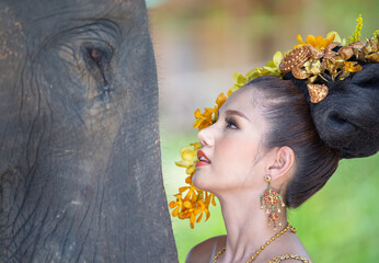 Asian Woman with traditional thai dress look at her cute elephant, relationship between people and animals.