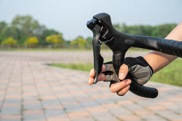Cropped shot of cyclist hand wearing glove and holding a road bike brake. Brake is use to reduces...
