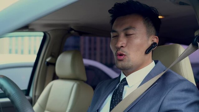 a business man driving a car speaking by using wireless headphones
