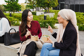 Young multiracial business women eating outdoor healthy food