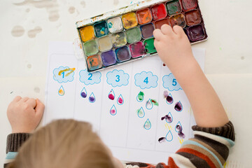 Early education, learning to count. 2 year old boy puts correct amount of stamps to assigned...
