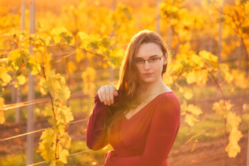 Teenage girl making a catlike gesture in a vineyard with yellow leaves on a sunny fall day in rural Germany.