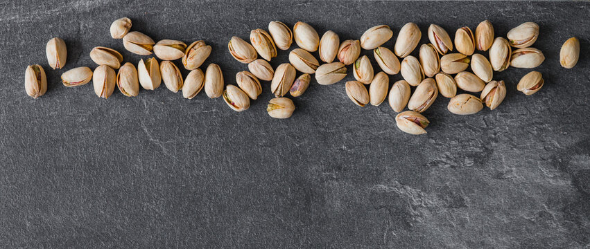 Composition with organic pistachio nuts on dark background. Space for text