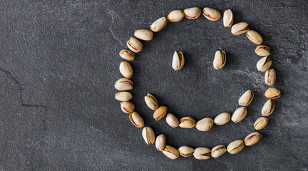 Smiley smiling with pistachios on a black background. The concept of healthy eating