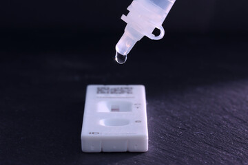 Dropper for a covid 19, lateral flow test. Focus is on dropper with the generic test cassette below. Shallow depth of field.