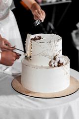 A wedding cake. Milk-colored cake decorated with cotton beads and gold leaf on a dark background in wedding day