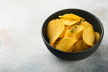Potato chips. Fast food. Crispy potato chips ceramic black bowl with sour cream sauce and onions in wooden stand on gray kitchen table concrete background. American tradition. Hot BBQ. Top view.
