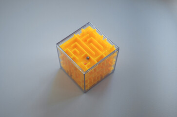 A transparent cube with mazes and a ball.A toy for the development of logic on a white background.