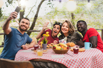 Multiracial friends relaxing taking selfie at picnic table - Young people having fun together celebrating, eating brunch outdoors at the countryside terrace - Friendship, youth and summer concept