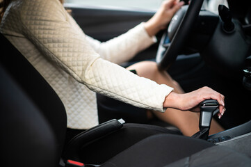 Fototapeta Close up of hand of female driver shifting gear stick before driving car obraz