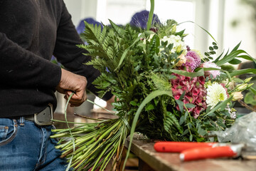 Junge Floristin bindet Schnittlbumenstrau&szlig; in der G&auml;rtnerei